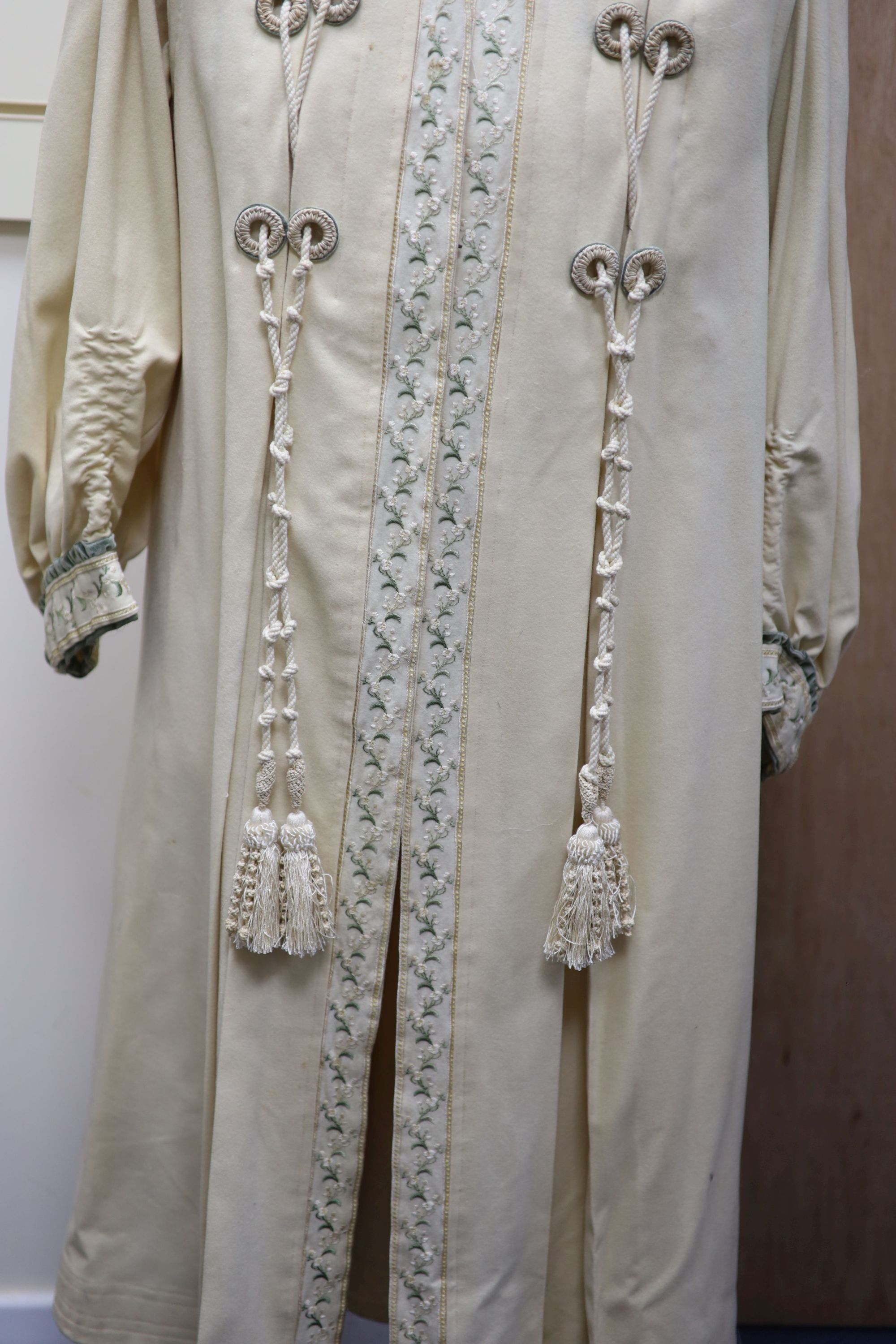 An Edwardian ladies fine cream wool coat with embroidered cuffs front edging and collar and ornate corded tasselling,